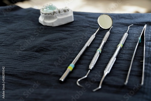 Closeup of dental tools on a blue cloth surface with a white ceramic teeth sample
