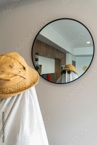 Vertical shot of a person in a funny ghost costume looking in the mirror