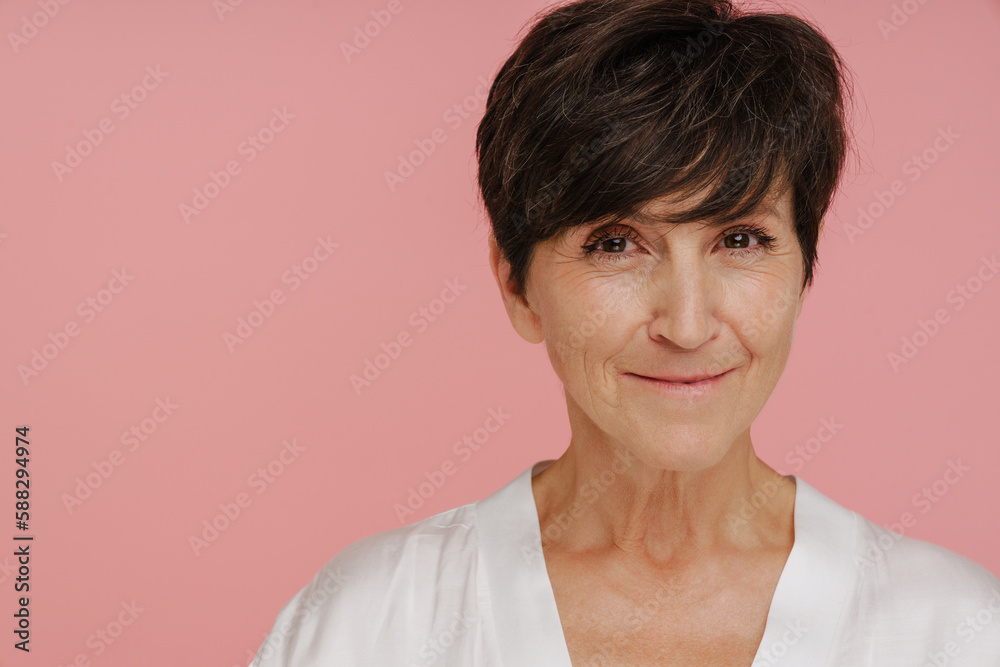 Senior woman smiling at camera while standing isolated over pink background Senior woman smiling at camera while standing isolated over pink background