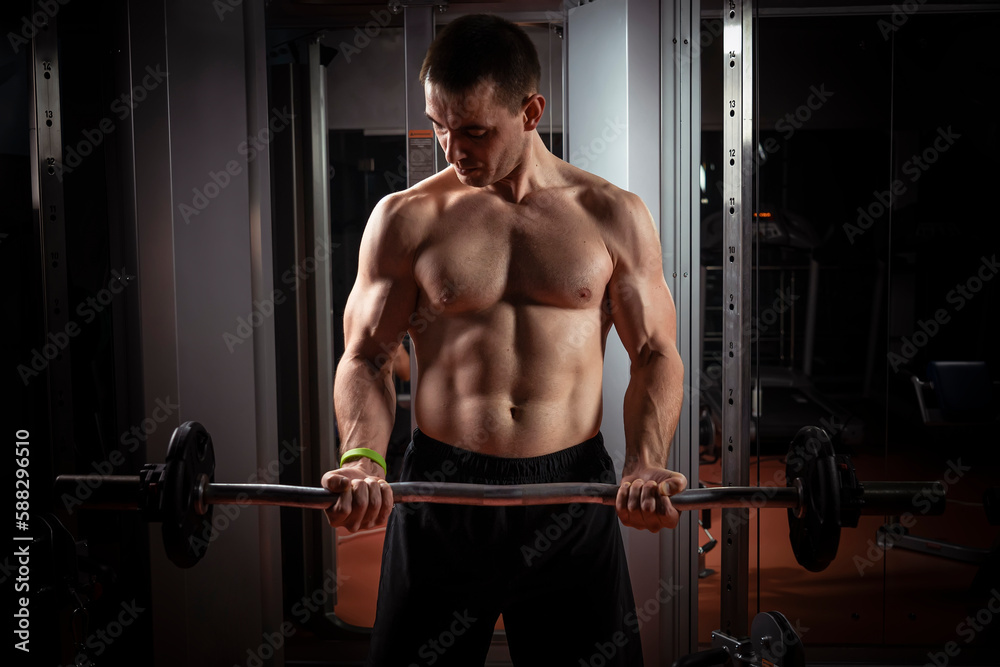 Strong man - bodybuilder with dumbbells in gym, exercising with a barbell Strong man - bodybuilder with dumbbells in gym, exercising with a barbell