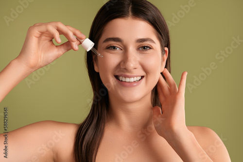 Laughing woman applying cosmetic serum