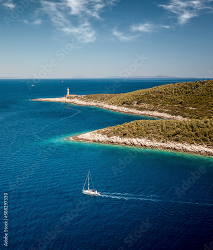 Aerial view of Stoncica lighthouse and a sailing boat on the island of Vis during summer, Dalmatia, Croatia. photo