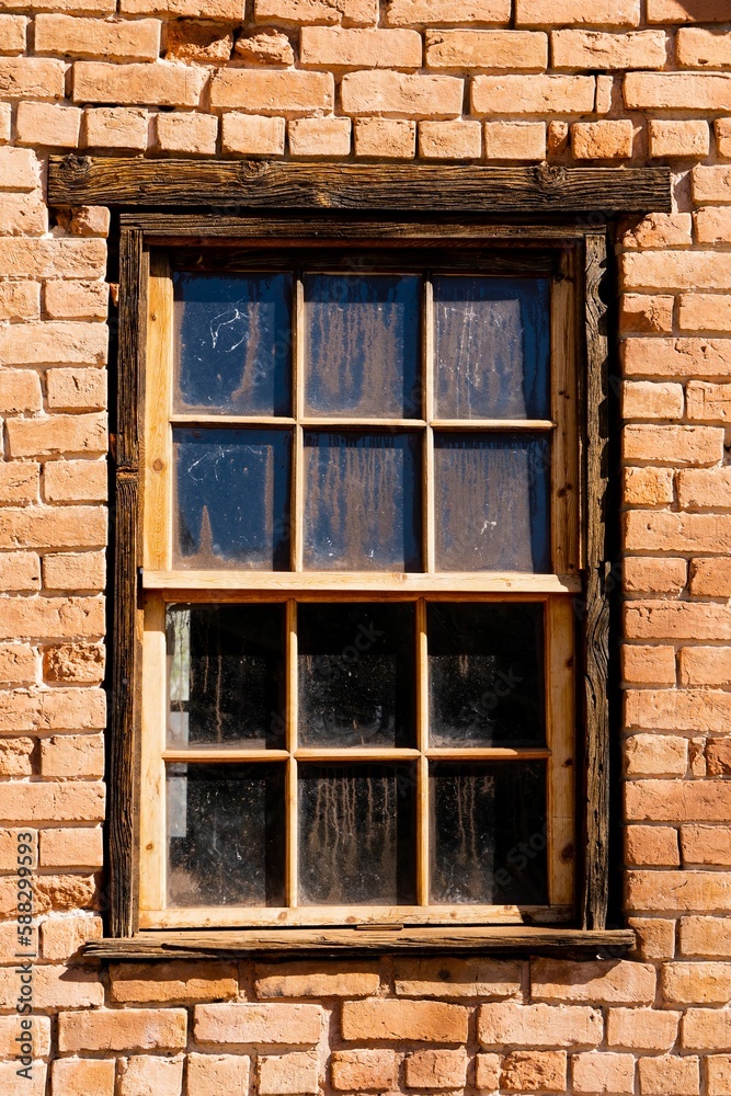 Closeup of a window with a wooden frame and an old red brick wall with damaged texture Closeup of a window with a wooden frame and an old red brick wall with damaged texture