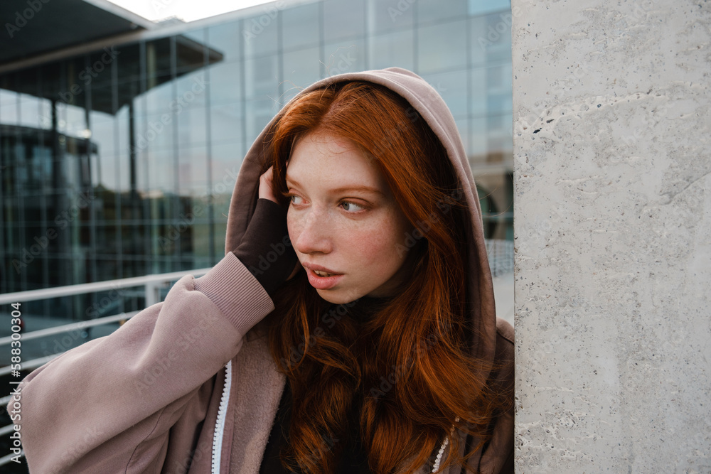 Redhead girl looking aside while standing outdoors