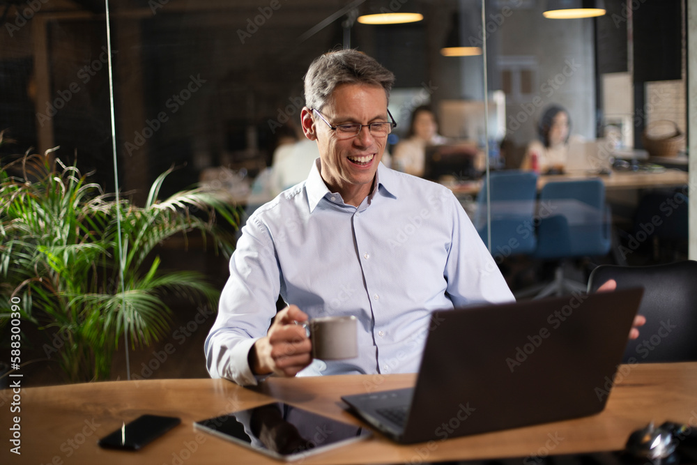 Businessman working with laptop at office. Businessman sitting at office desk working on laptop computer.. Businessman working with laptop at office. Businessman sitting at office desk working on laptop computer..