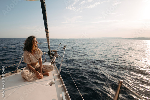 Woman sitting on sailboat at sunset photo