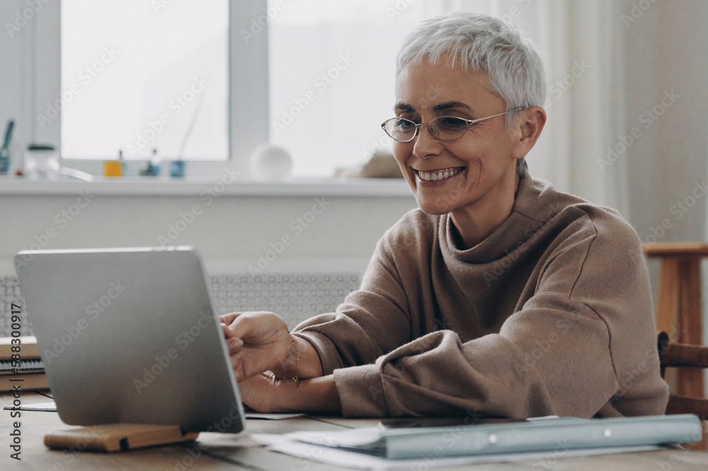 Happy senior businesswoman using digital tablet while sitting at her working place Happy senior businesswoman using digital tablet while sitting at her working place