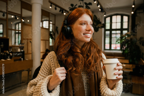 Young smiling girl holding coffee while standing in cafe