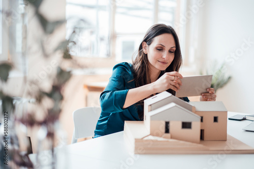 Young businesswoman making house model at home office