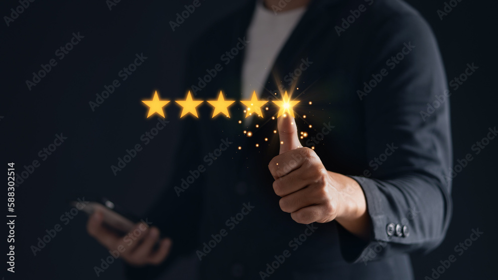 A satisfied customer gives a thumbs up for a five-star rating on his mobile phone, showing his positive feedback. - obrazy, fototapety, plakaty 