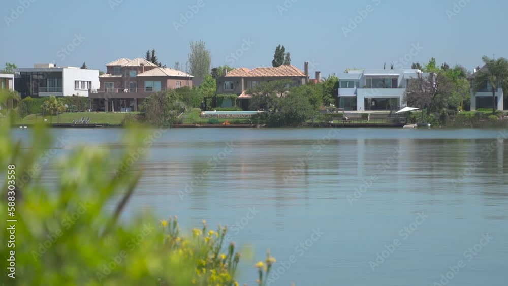 Wide shot of luxury residential villas with lake view during sunny day - static 4K Wide shot of luxury residential villas with lake view during sunny day - static 4K