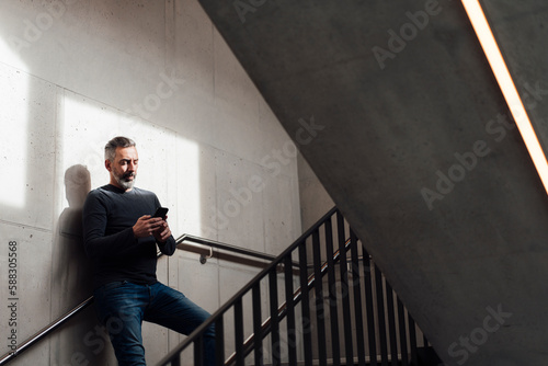 Businessman using smart phone on staircase photo