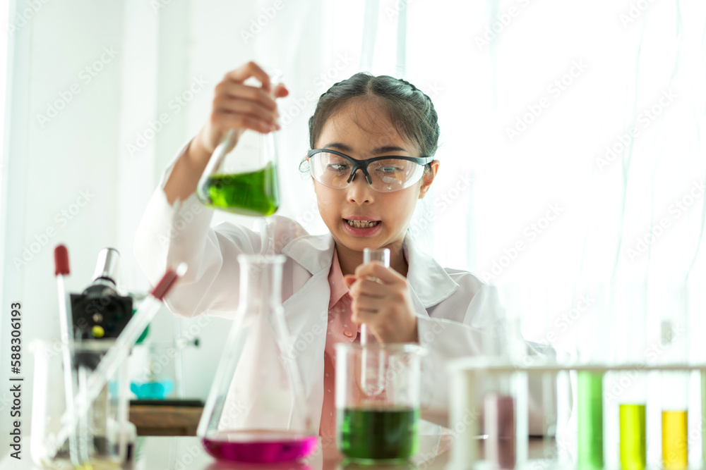 Cute little girl student child learning research and doing a chemical experiment while making analyzing and mixing liquid in glass at science class in school.Education and science concept