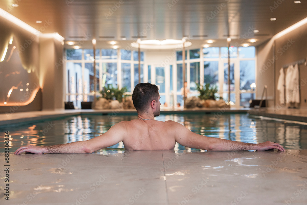 Young man swimming in a swimming pool in a luxury hotel. Enjoying beautiful leisure near the SPA.