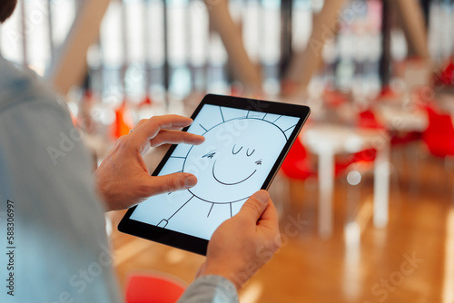 Businessman zooming design of sun on tablet PC in office