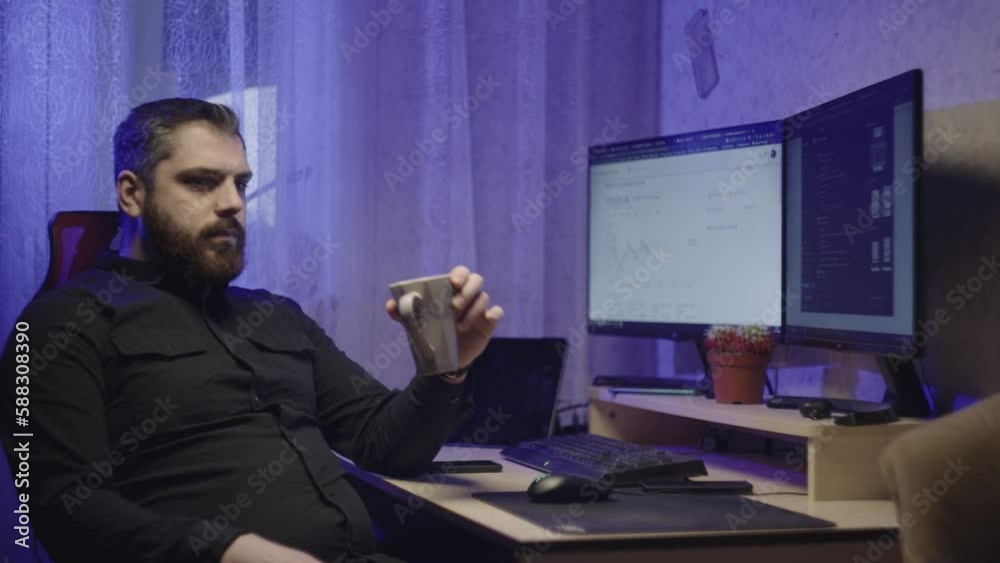 A businessman works at a computer at home and drinks coffee from a cup on the break. Online work of a man. High quality 4k footage A businessman works at a computer at home and drinks coffee from a cup on the break. Online work of a man. High quality 4k footage