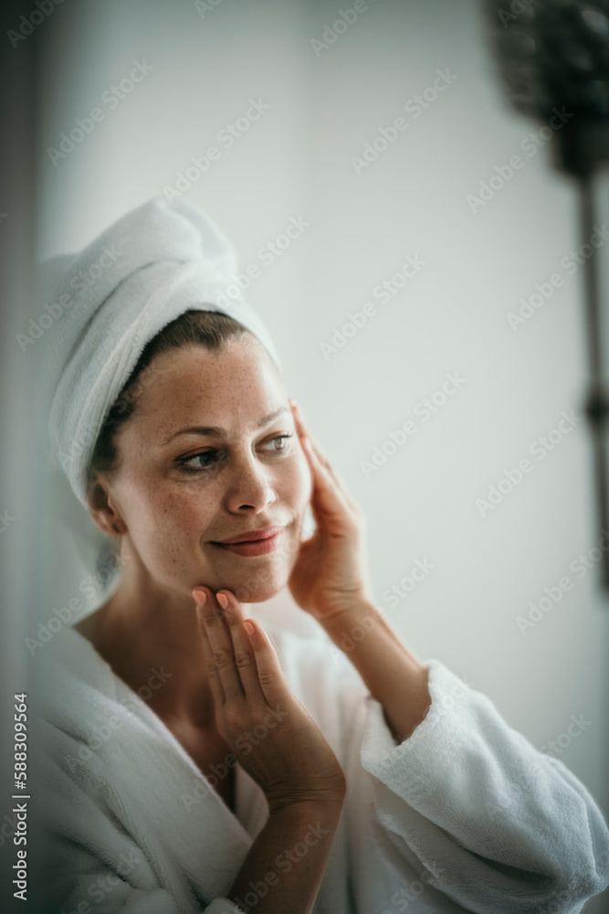 Woman checking skin looking in mirror at home Woman checking skin looking in mirror at home