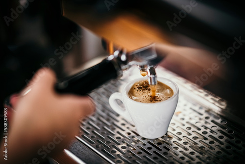 Espresso shot dripping in cup through coffee maker