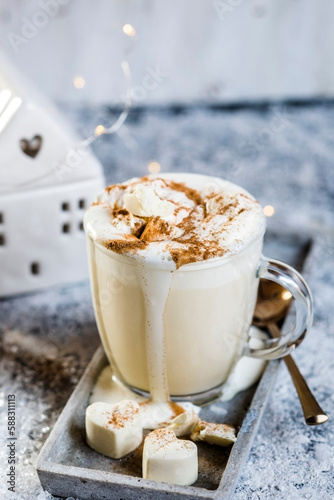 Mug of hot white chocolate with whipped cream and cinnamon