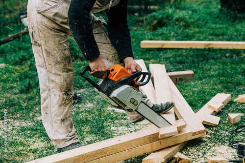 Carpenter cutting wood with chainsaw on grass photo