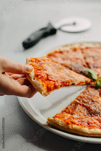 Traditional Italian pizza, vegetables, ingredients on a light background.Pizza menu. Side view. piece of pizza in hand.