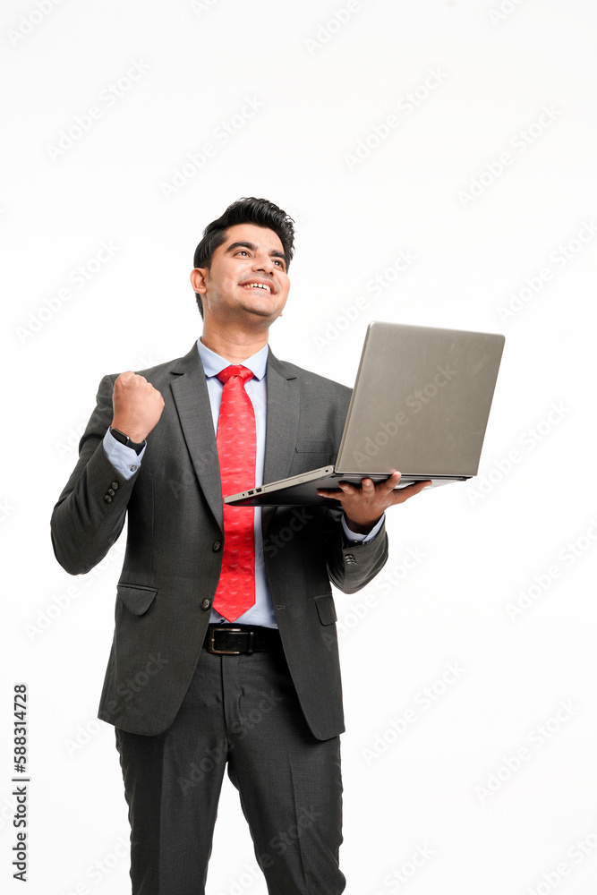 Young indian businessman in suit, holding laptop and giving a winning expression. Young indian businessman in suit, holding laptop and giving a winning expression.