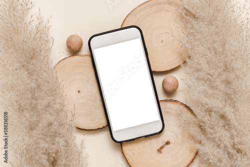 Smartphone with white screen on wooden podium with pampas grass, aesthetic mobile background. Mobile phone mockup for invitation, promotion, online shopping, website branding and business template