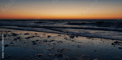 K  ste und Strand der Nordsee im gl  henden Sonnenuntergang mit Schaum von den Wellen und Brechern