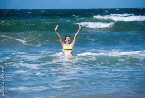 A woman in a swimsuit rejoices and has fun in the sea on the waves © Александр Довянский