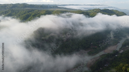 Amazing aerial view of beautiful low clouds creeping on the tree-covered mountain slopes