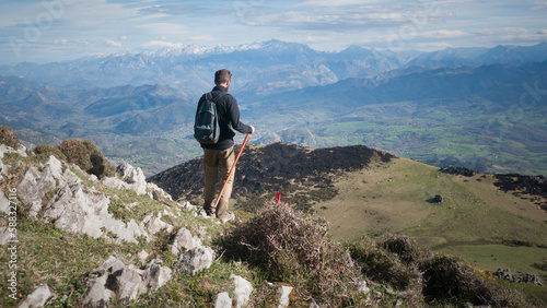 Fototapeta Naklejka Na Ścianę i Meble -  Hombre joven barbudo descendiendo por ladera de montaña de Asturias