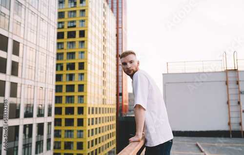 Thoughtful man leaning on railing on roof of building