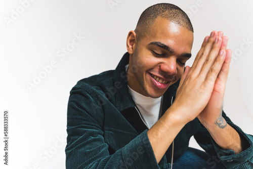Foto Happy young adult Christian man praying with joined palms