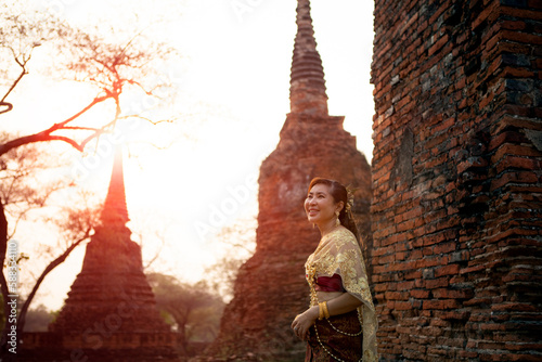 beautiful asian woman wearing thai tradition dress standing against brick wall at old temple of ayutthaya world heritage site of unesco thailand photo