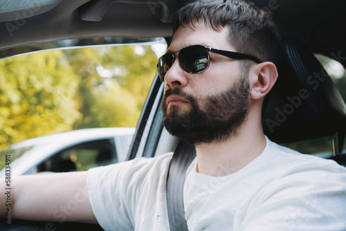 caucasian bearded man in sunglasses driving car