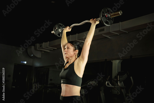 woman training with heavy barbell in modern gym