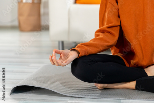 Yoga mindfulness meditation. Woman hands in chin mudra gesture. African girl practicing yoga at home. Woman sitting in lotus pose on yoga mat meditating relaxing indoor. Girl doing breathing practice