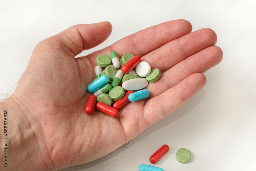 Hand is holding and showing some medicine pills on white background Hand is holding and showing some medicine pills on white background