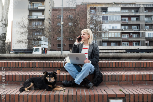 Young female student sitting outdoor with her adopted dog looking for a new apartment to rent because she was evicted by her landlord for forbidden of keeping pets photo