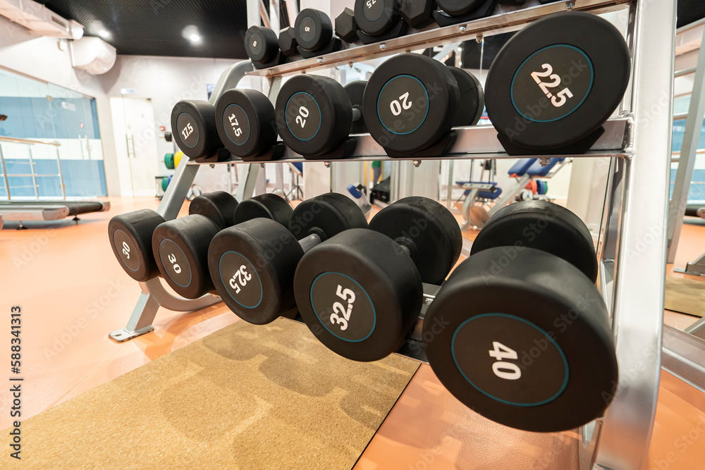 heavy black metal dumbbells for strength training on rack. heavy black metal dumbbells for strength training on rack.