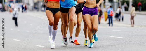 group female runners run marathon. slender legs girls running city race, summer sports event