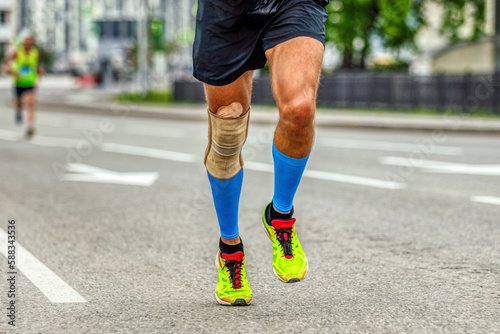 legs man runner in knee pads and compression socks running marathon, protection knee sleeve after injury to stabilization
