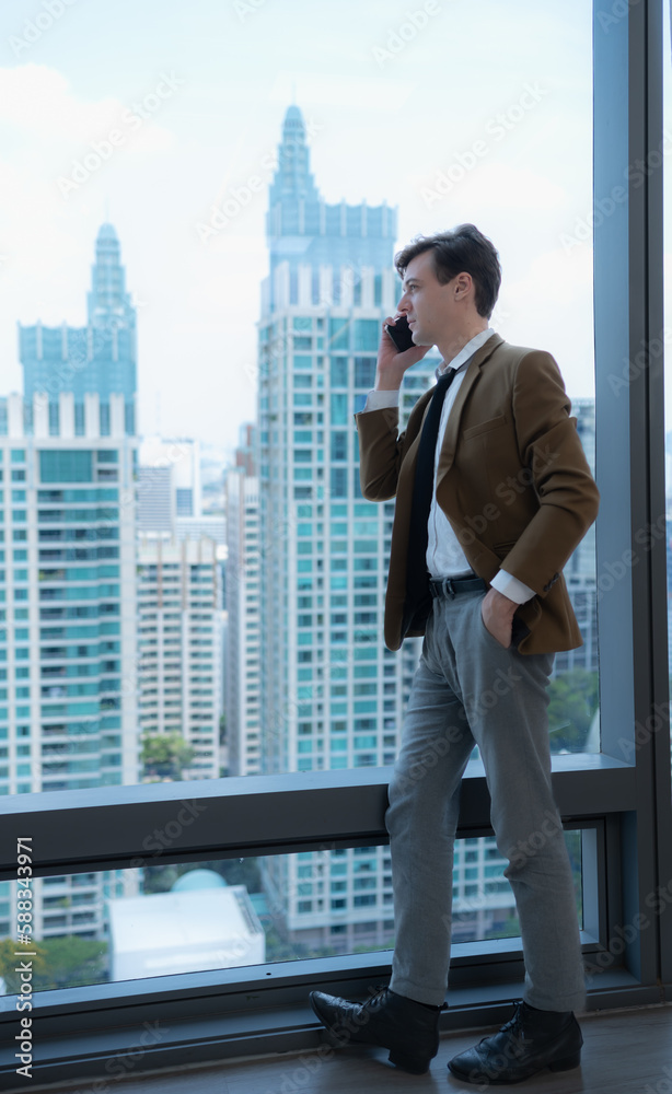 Young businessman sit and relax in the relaxation room by the window overlooking the beautiful city buildings. along with the phone to talk about business. Young businessman sit and relax in the relaxation room by the window overlooking the beautiful city buildings. along with the phone to talk about business.