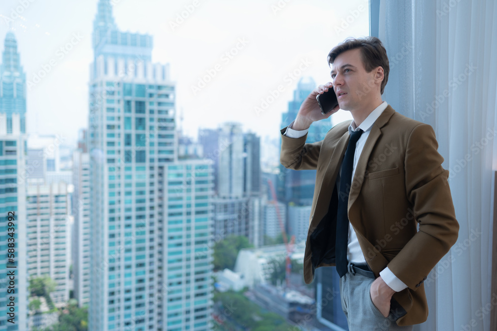 Young businessman sit and relax in the relaxation room by the window overlooking the beautiful city buildings. along with the phone to talk about business. Young businessman sit and relax in the relaxation room by the window overlooking the beautiful city buildings. along with the phone to talk about business.