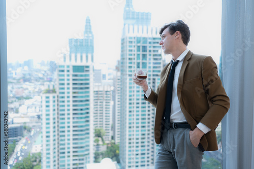 Young businessman sit and relax in the relaxation room by the window overlooking the beautiful city buildings.