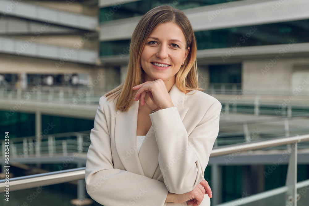 Fototapeta premium Smiling businesswoman standing against modern office building