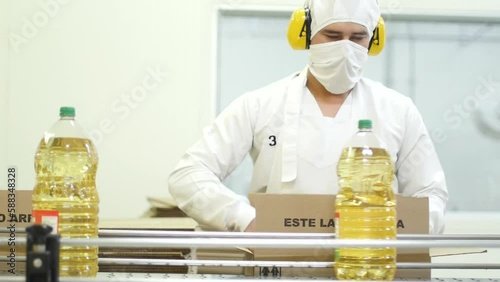 Male factory worker boxing sunflower oil in the product line-HD photo