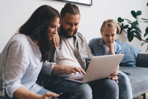 Happy family browsing netbook while sitting on couch in living room