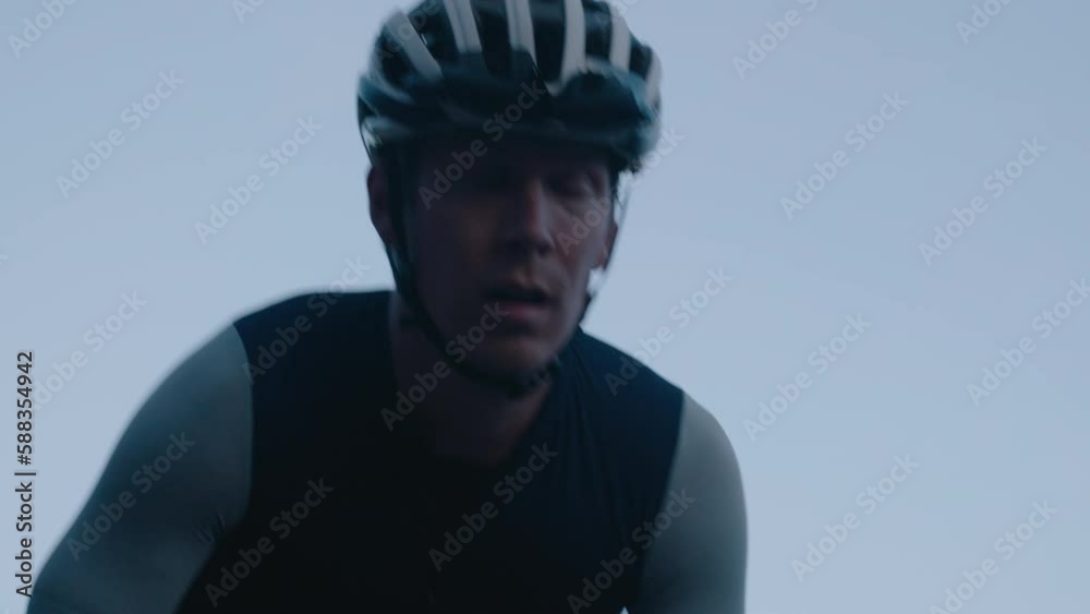 Concentrated and tired professional cyclist ride up mountain road. Steep hill effort by slim athletic man in tight lycra jersey and bibs on carbon lightweight bike Concentrated and tired professional cyclist ride up mountain road. Steep hill effort by slim athletic man in tight lycra jersey and bibs on carbon lightweight bike