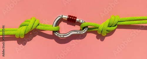 carabiner with a rope lies on a colored background. Equipment for climbing and mountaineering. Safety rope. the concept of reliability and strength.